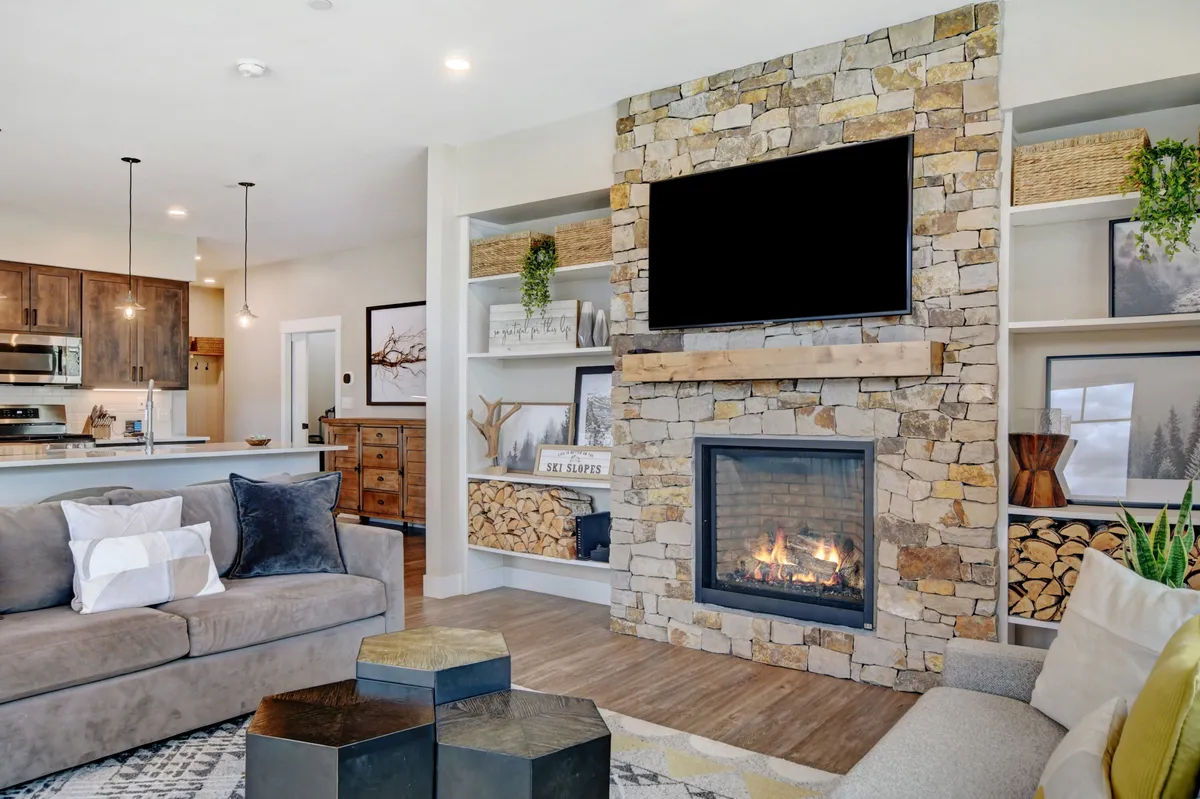 A close view of a living space that highlights a crackling fireplace, built-in bookshelves filled with games and books, a cozy sofa, and a coffee table—all arranged to create a setting for relaxation, entertainment, and quality time together.