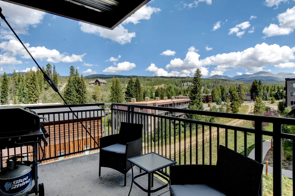 An exterior balcony scene featuring comfortable outdoor furniture, a barbecue grill, and expansive mountain views. The tranquil setting invites guests to relax, dine al fresco, or simply take in the breathtaking Colorado landscape.