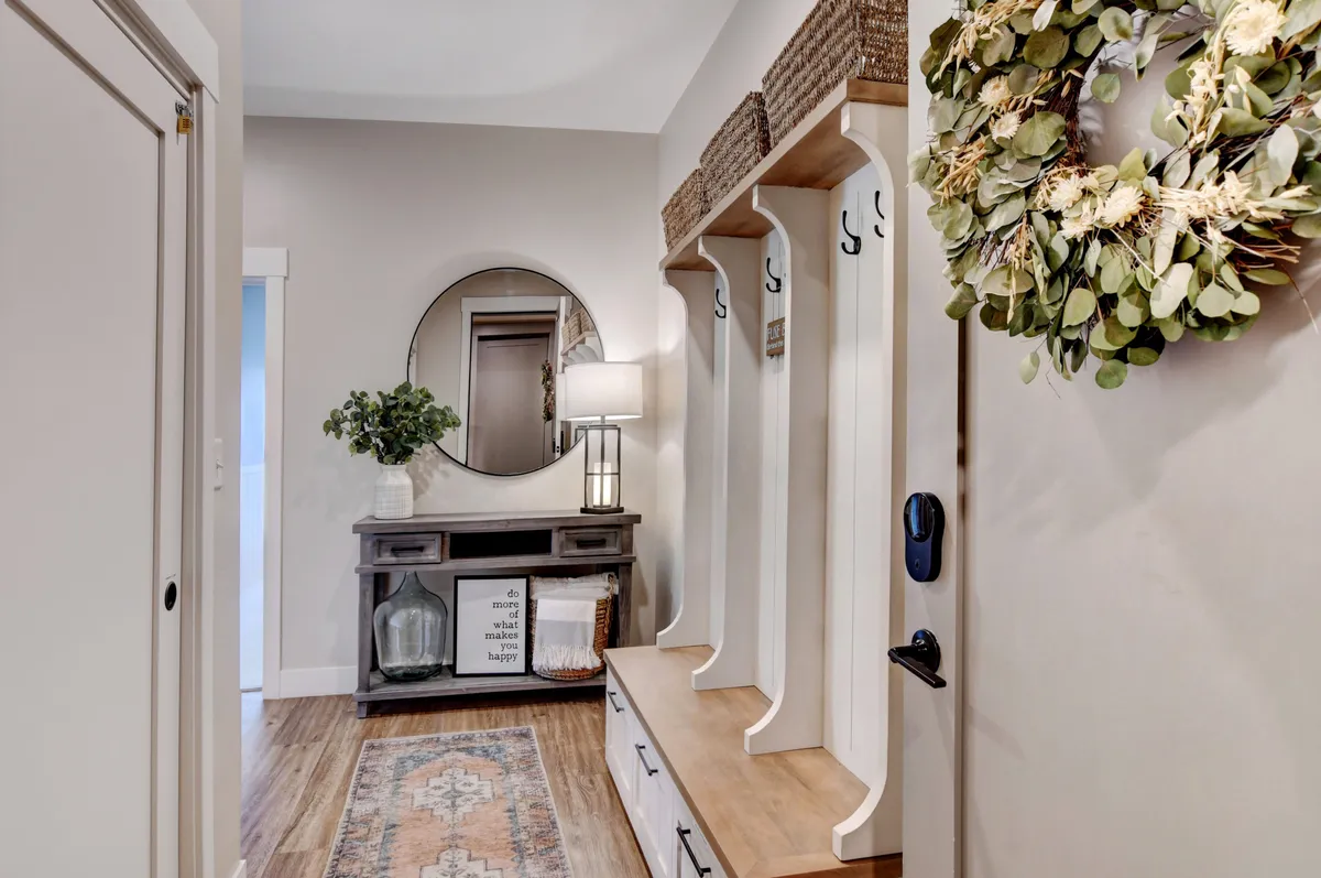 This image showcases a well-designed entryway with a mirror, hooks for coats and gear, a console table, a welcoming wreath, and a well-placed rug. The space is organized and inviting, perfect for stowing boots, jackets, and outdoor equipment after a day of adventure.