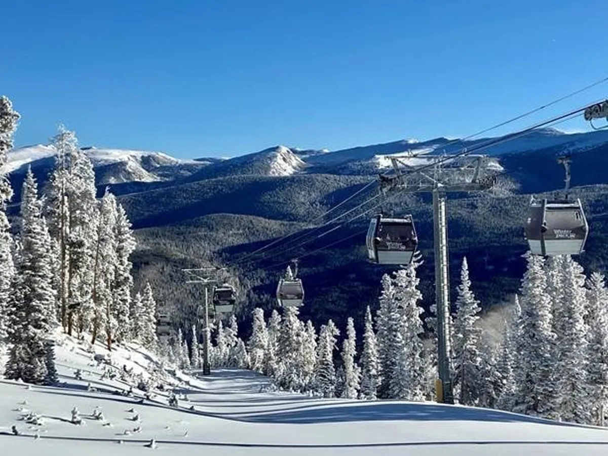 A scenic exterior shot featuring a gondola lift ascending past snow-covered trees with a majestic mountain range in the background. The scene evokes the thrill of winter sports and the stunning beauty of the alpine landscape, inviting viewers to imagine themselves skiing, snowboarding, or simply taking in the sweeping views.