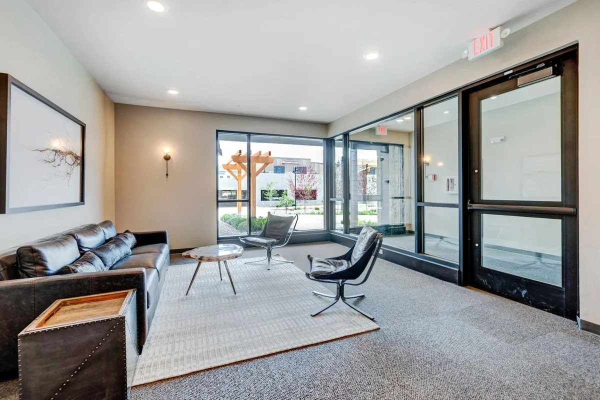 A welcoming living room with a plush sofa, coffee table, armchairs, and expansive windows that flood the space with natural light. The seating arrangement invites relaxation or socializing.