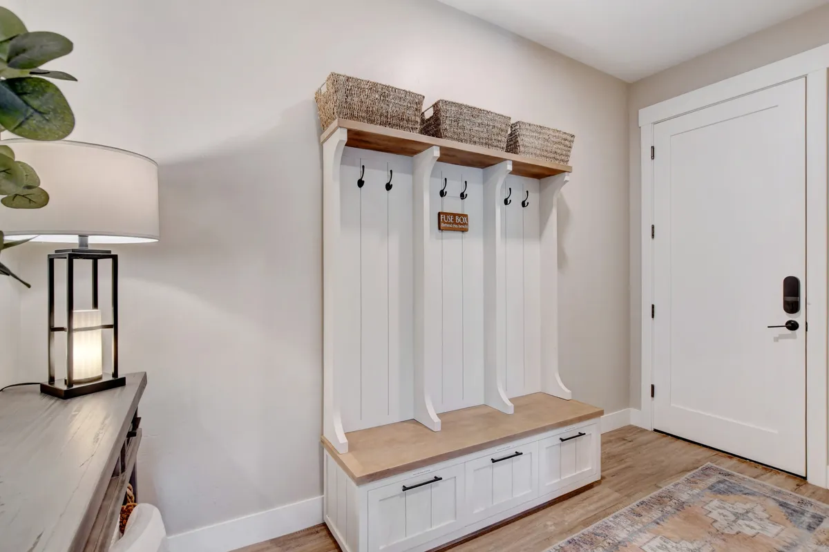 A functional mudroom featuring a cozy bench, woven baskets, and hooks lined with coats, suggesting readiness for outdoor excursions. The space is bright and inviting, with an organizational focus that hints at frequent comings and goings, perfectly suited to an active, exploration-rich lifestyle.